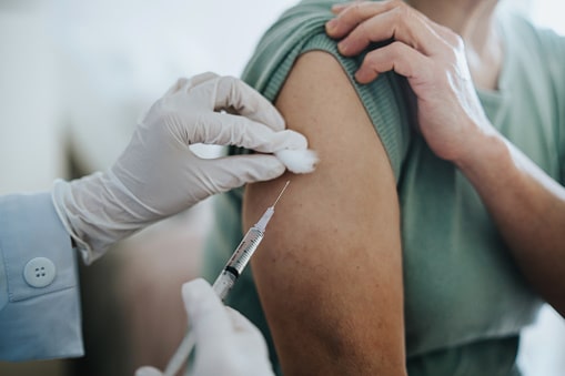 A close up of a woman getting the Covid-19 vaccine in her arm.