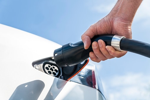A person plugs in their electric vehicle.